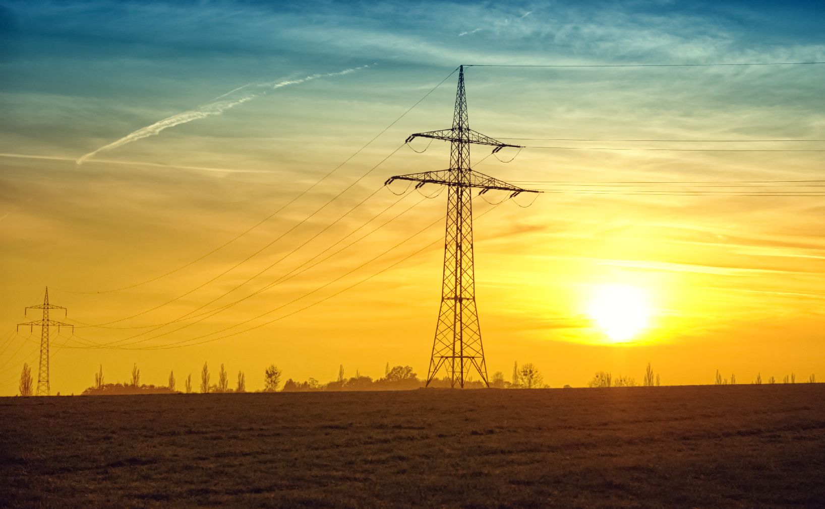 Utility poles in field at sunset