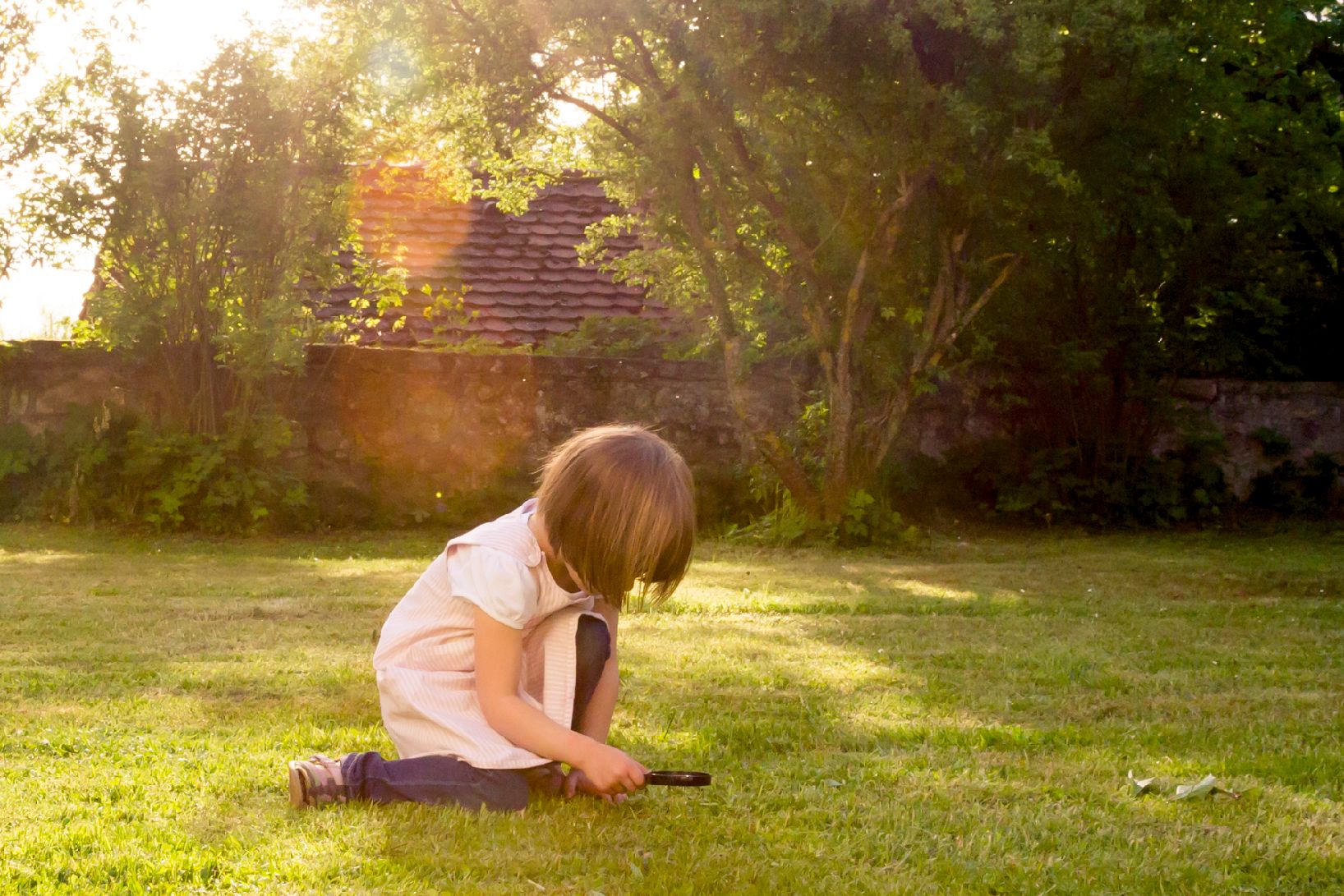 Child looking at grass through a magnifying glass